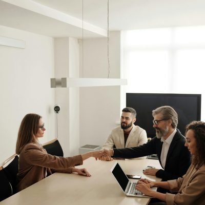 Business professionals engaging in a handshake across a conference table, signifying successful collaboration.